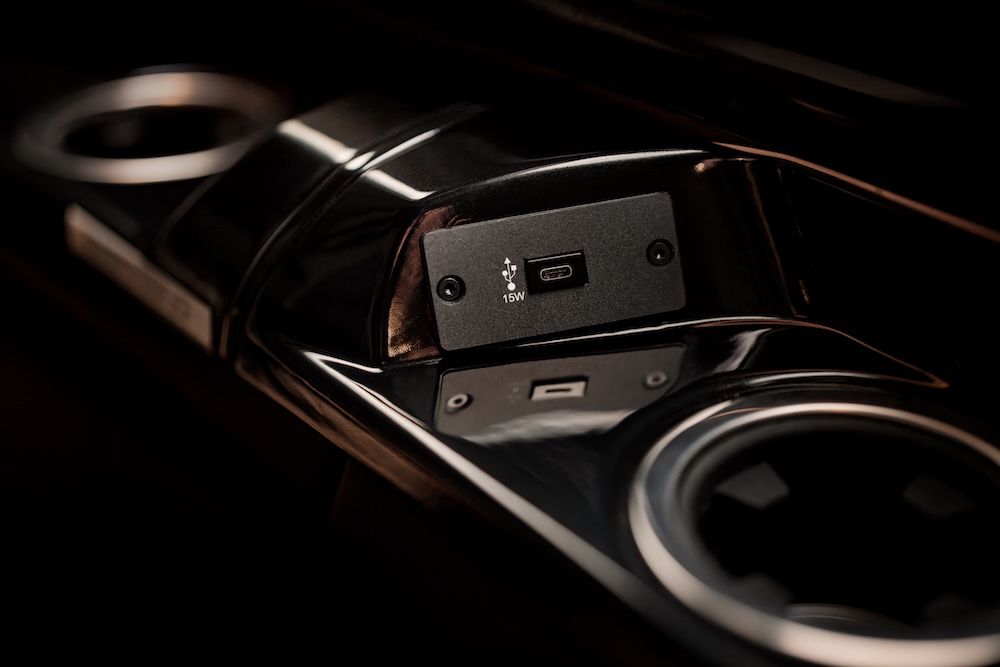 Close-up of a glossy black cabin side console in the G3 Vision Jet featuring a 15W USB-C charging port set between two cup holders.