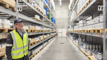 AkzoNobel completes key phase of €22m Pamiers coatings investment A worker in a hi-vis vest stands in an aisle of a coatings warehouse lined with shelving bays of stacked paint containers