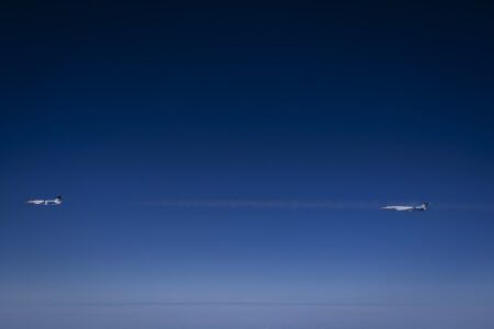 Two business jets flying in formation against a deep blue sky at high altitude