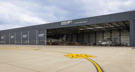 A row of business jets undergoing maintenance inside the ExecuJet MRO Services hangar in Belgium, viewed from the apron.