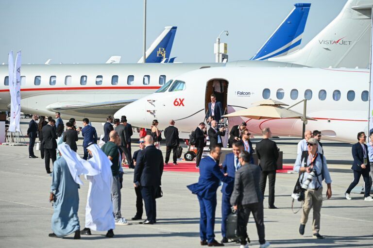 Business jets including a Dassault Falcon 6X and a VistaJet aircraft on static display, surrounded by attendees at an outdoor business aviation show