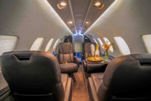 The refurbished cabin interior of a business jet, with brown leather seating, a folding table and window blinds