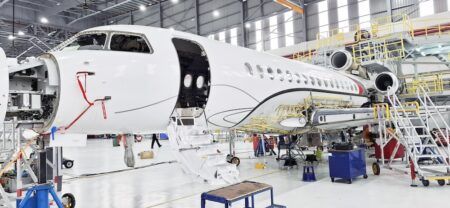 ExecuJet MRO Services Malaysia completes Falcon 8X C-check Aircraft in a maintenance hangar with open nose section and cabin door, surrounded by access platforms and ground equipment