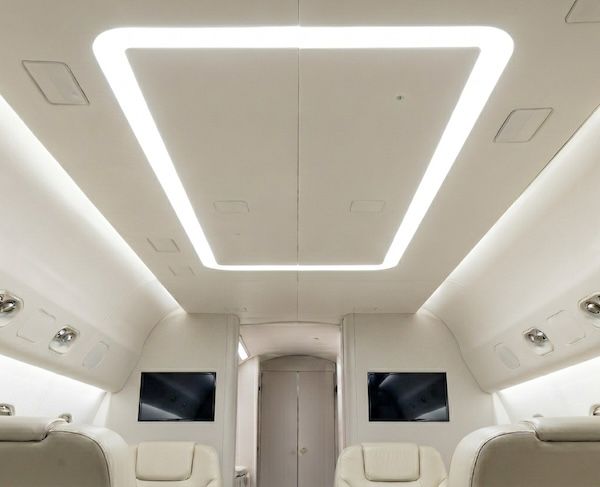Illuminated rectangular halo light fixture set into the ceiling of a white business jet cabin