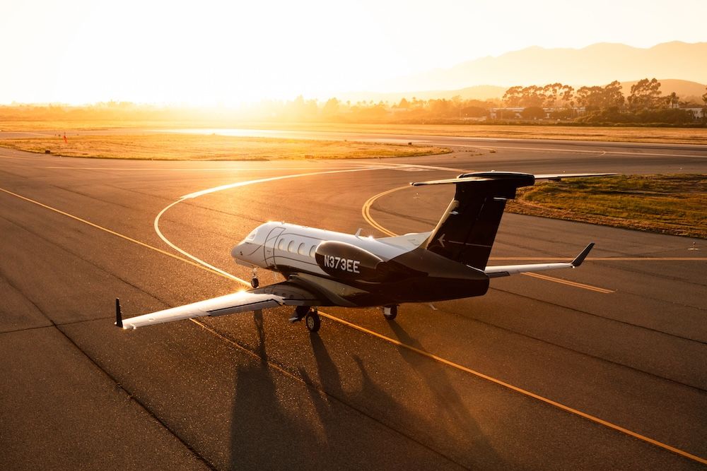 Embraer Phenom 300EV light jet on an airport ramp at sunset