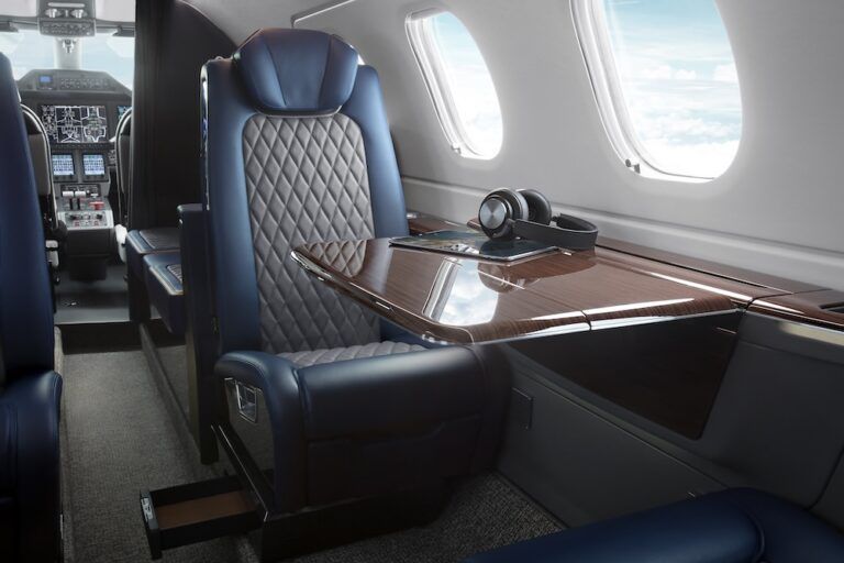 ANAC, FAA and EASA certification for Embraer’s Phenom 300EV Phenom 300EV cabin interior showing a blue and grey leather seat and wood veneered table with headphones