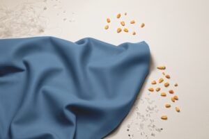 A blue textile swatch from Tapis's Volar Test displayed alongside corn kernels and glass fragments.
