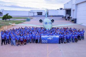 Large group of employees in front of unpainted business jet