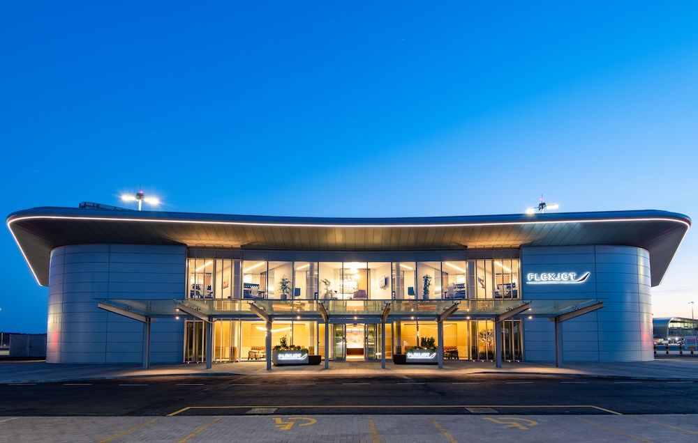Exterior photo of curved terminal building lit up at dusk