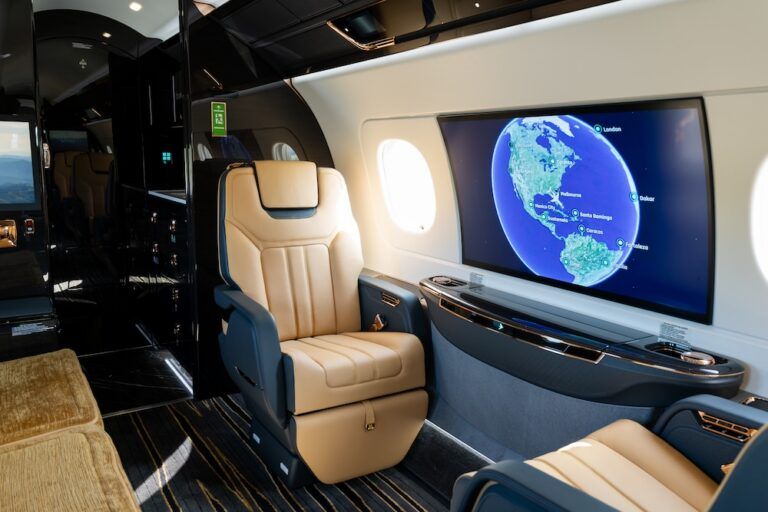 Flexjet takes delivery of first Praetor 600E Tan leather cabin seat next to a large sidewall screen displaying a flight route map