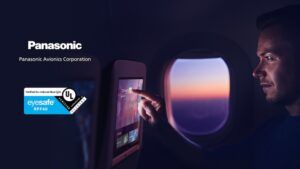 Passenger touching an IFE screen beside an aircraft window at dusk, with Panasonic and Eyesafe certification logos displayed