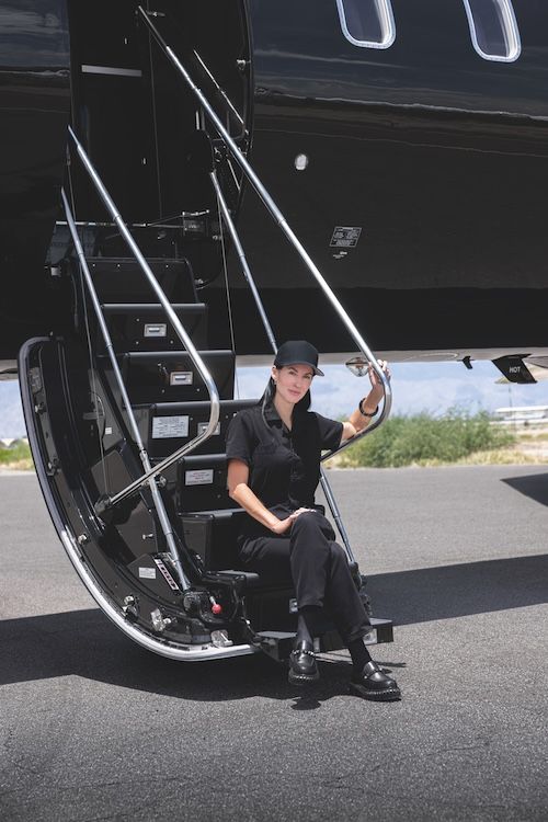 Sarah Mespelt Larranaga sitting on the airstairs of a private jet