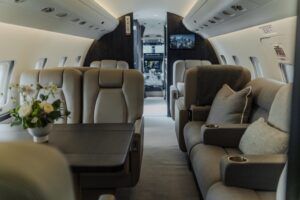 Business jet cabin with beige club seats and divan