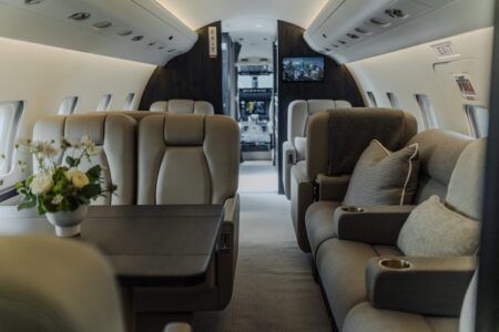 Business jet cabin with beige club seats and divan