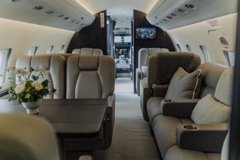Business jet cabin with beige club seats and divan