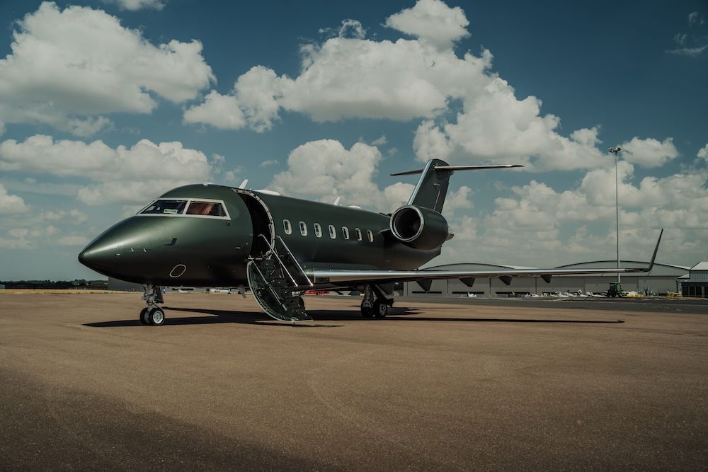 Matte green business jet parked on apron with airstair deployed