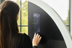 A woman touches the surface of a cabin divider, where a touchscreen displays a moving map.