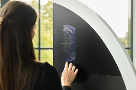 A woman touches the surface of a cabin divider, where a touchscreen displays a moving map.