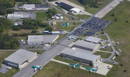 Aloft unveils Innovation Lab and celebrates 50th anniversary Aerial view of ALOFT AeroArchitects’ campus at Delaware Coastal Airport, with several large grey hangars and four Boeing 737s in green protective coating parked outside.