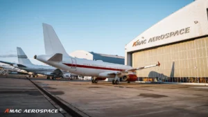 White Airbus narrowbody outside a large AMAC Aerospace hangar