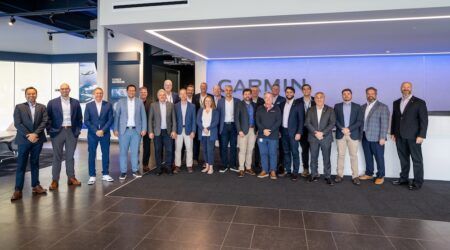 Embraer Supplier Advisory Council meets to discuss projects Group of executives posing in front of Garmin sign