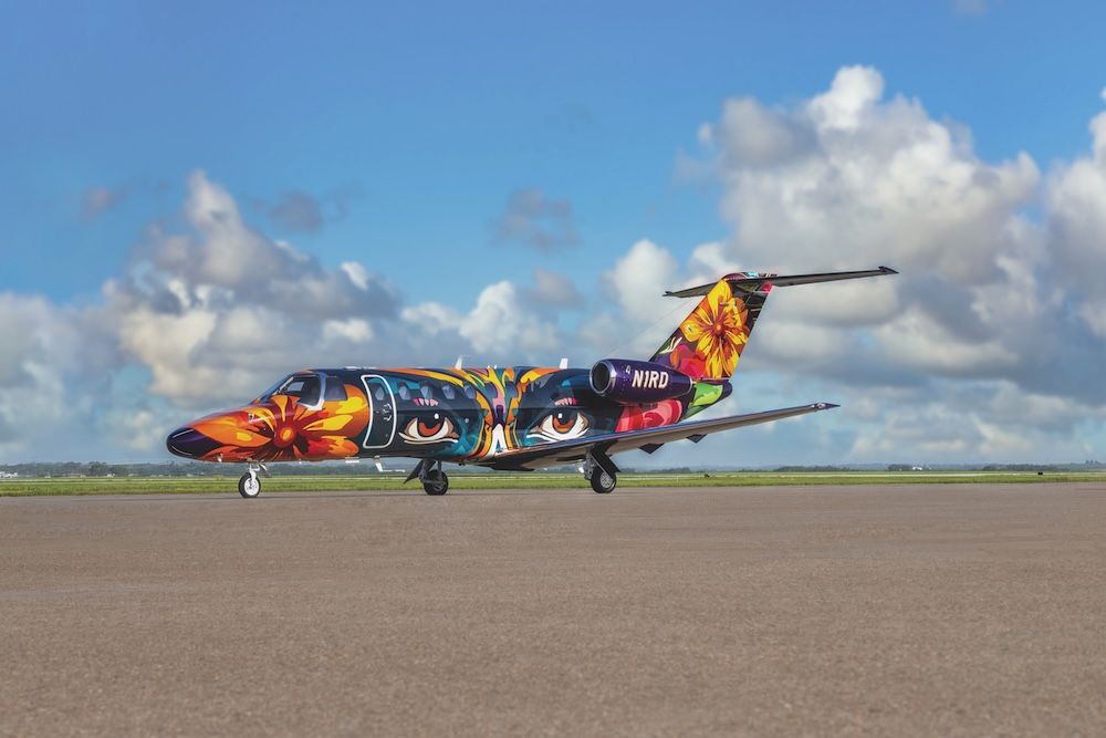 Citation CJ3+ jet registered N1RD, painted in a vivid multicoloured livery with large eyes and flowers, parked on a ramp under a cloudy sky
