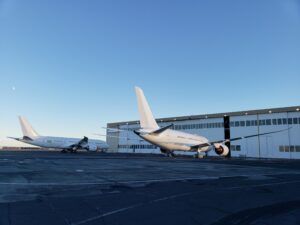 Two BBJ 787 aircraft parked on apron in front of large hangar building