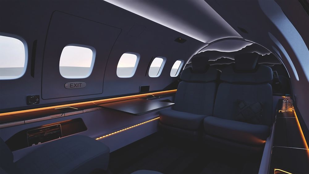 Rendering of a light jet cabin in dark tones with amber accent lighting, a fold-out table, two seats and a backlit bulkhead